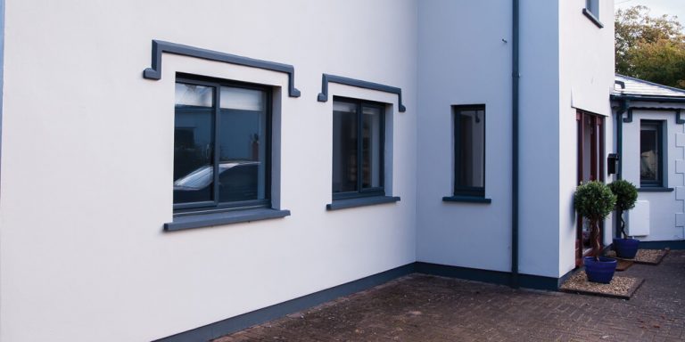 Aluminium casement windows on a white modern house exterior with dark grey frames and trim.